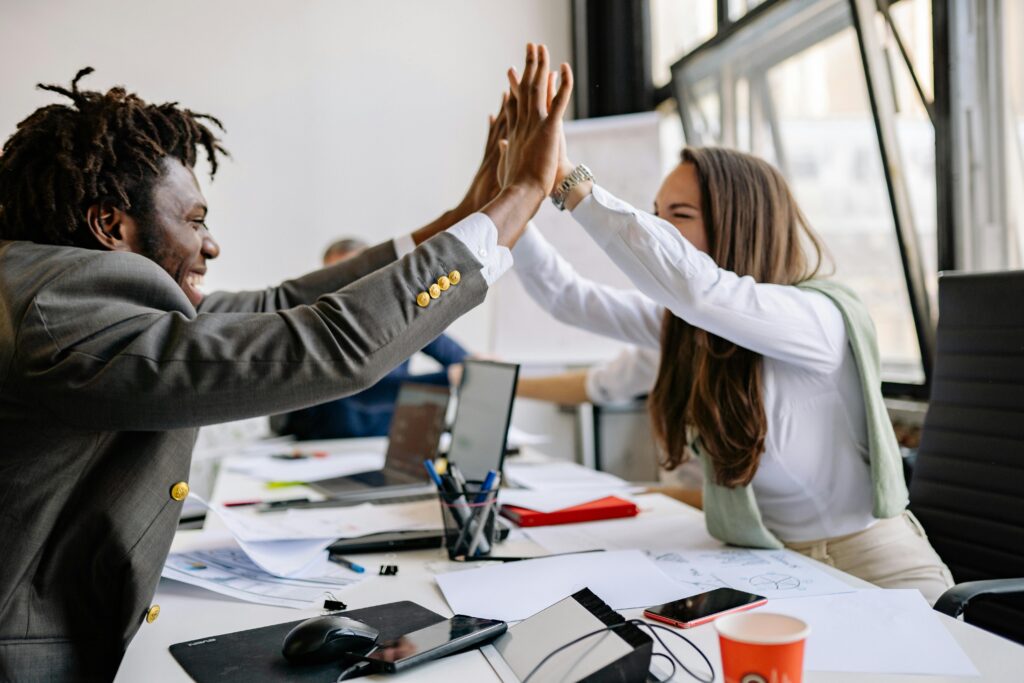 Multiracial colleagues celebrating a successful meeting with a high five in a modern office setting.